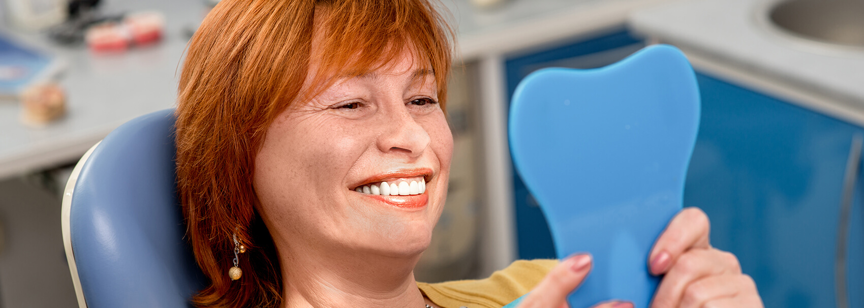 woman examining her smile in a mirror