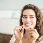 photograph of young woman holding invisalign clear aligners, can I use invisalign with dental crowns